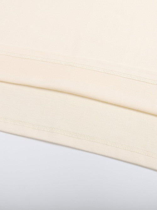 Detailed view of hem stitching on beige Mark the Believer Tee. Durable 100% cotton fabric for long-lasting casual wear.