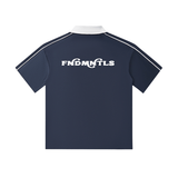 Rear view of navy short-sleeve polo shirt with white collar and 'FNDMNTLS' branding across the upper back.