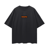 FNDMNTLS. Shattered Tee in black with orange logo on chest, oversized fit and deep drop shoulders for unisex streetwear style.