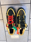 Pair of black and yellow sneakers with colorful laces on a tiled floor.