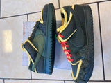 Pair of green and black sneakers with yellow accents on a tiled floor.