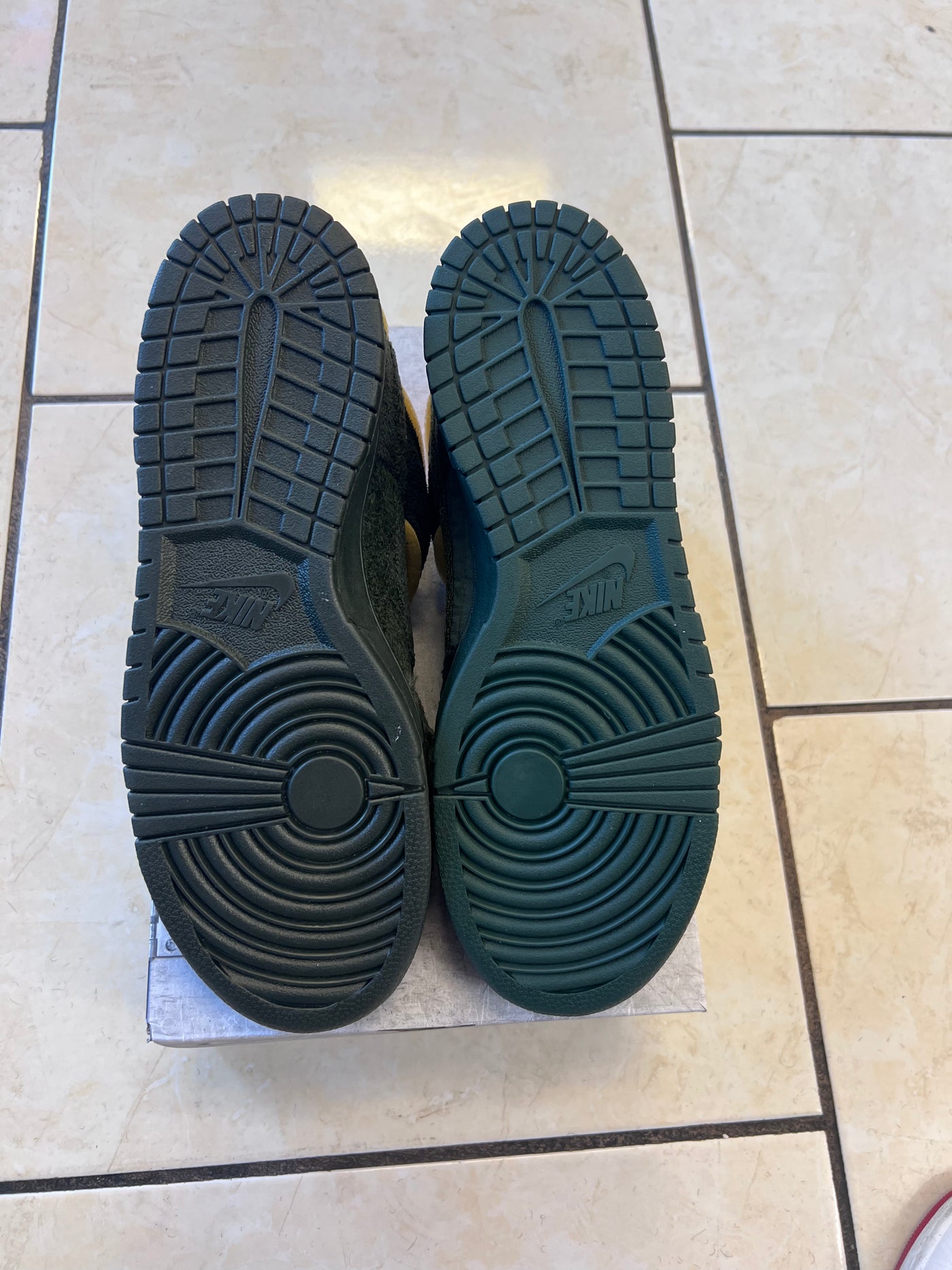 Black shoes with soles facing up on a tiled floor