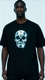 Person wearing a black t-shirt with a glowing skull design on a light gray background