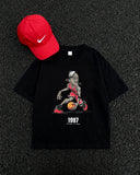 Flat lay of 1997 Flu Game Unisex Seamless Graphic T-Shirt - 230 GSM in black with red Nike cap, showcasing bold basketball-themed print.
