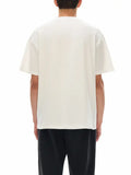 Back view of a person wearing a loose fit white graphic t-shirt made of 100% cotton with short sleeves and a classic round neck.