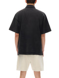 Black short-sleeved heavyweight snow-washed polo with bird emblem and beige shorts