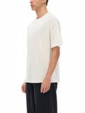 Man wearing cream-colored NBA logo graphic tee and black pants perfect for casual wear