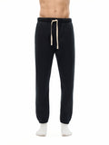 Model wearing black Essential Fleece Sweatpants with cream drawstring, showcasing a relaxed fit and cozy fleece material.