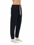 Side view of model in black Essential Fleece Sweatpants, highlighting the tapered leg and side pocket design for casual wear.