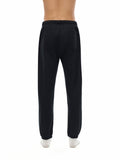 Rear view of model wearing black Essential Fleece Sweatpants with back pocket and elastic waistband for everyday comfort.