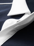 Detailed view of button placket under the white contrast collar on navy cotton blend polo shirt.