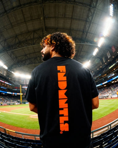 Back view of black Mets Orange Heavyweight T-Shirt featuring vertical orange FNDMTLS print, styled for casual MLB streetwear.