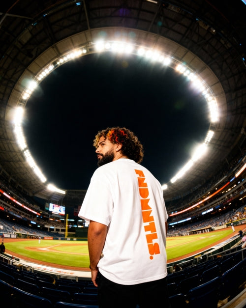 White Mets Orange Heavyweight T-Shirt with bold orange FNDMTLS back print, styled under stadium lights for unisex streetwear.