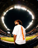White Mets Orange Heavyweight T-Shirt with bold orange FNDMTLS back print, styled under stadium lights for unisex streetwear.